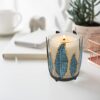 Southwest-style metal feather candle holder with removable glass hurricane chimney.
